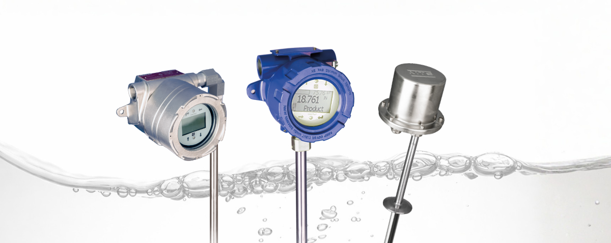 Detailní fotografie tří průmyslových hladinoměrů ponořených do kapaliny, umístěných nad zvlněnou vodní hladinou s viditelnými bublinami na světlém, čistém pozadí.